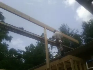 Carpenter setting a ridge beam over a new addition frame — Ice Dam Removal by Roofing Brothers in Howard City