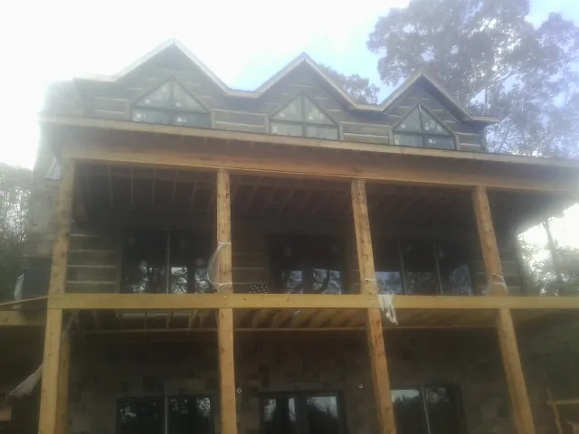 Dormers and porch framing on a large log home under construction — Roof Coating work by our crew in Howard City