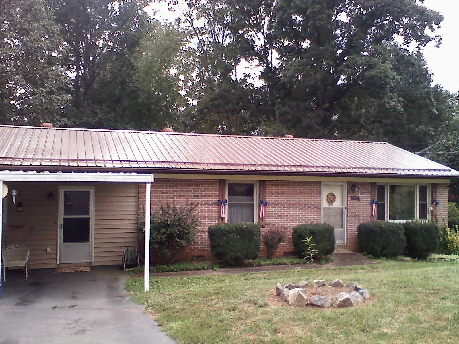 Bronze metal roof and carport on a brick ranch home — Roof Repair work by our crew in Howard City