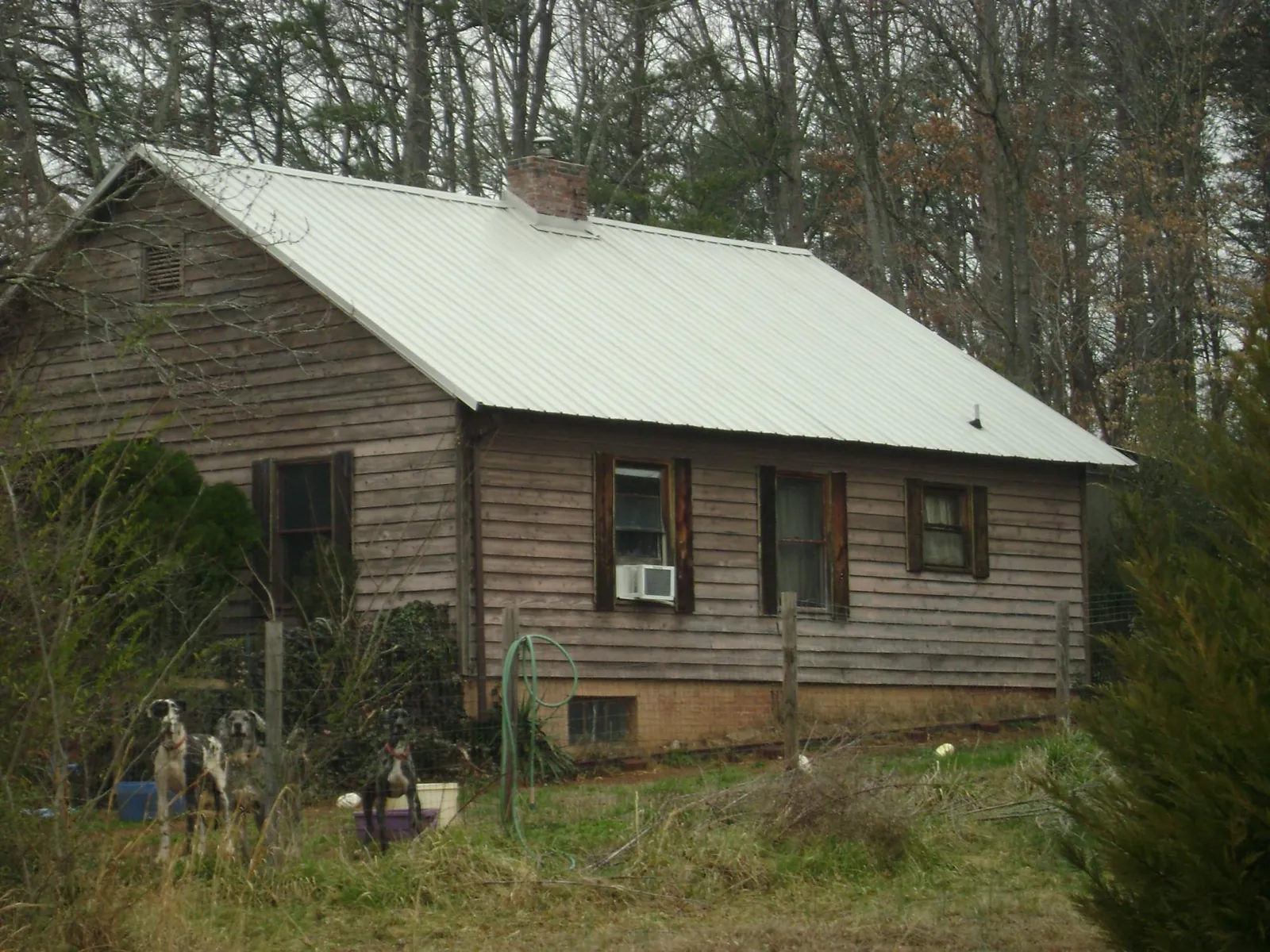 White metal roof on an old wood sided farmhouse, from a Metal Roof Installation job in Howard City